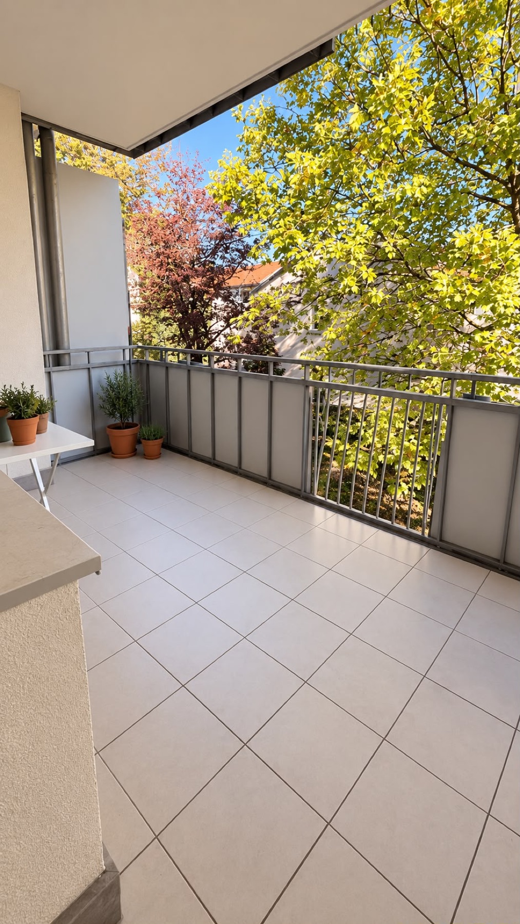 Covered loggia with potted plants and a view of sunlit trees